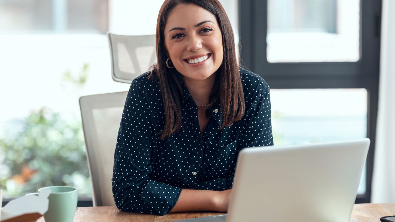 Woman sitting by a desk with a computer and a coffee cup